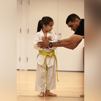 A man and girl in white uniforms are practicing karate.